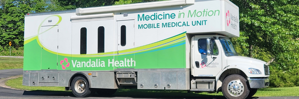 Green and white mobile medical unit vehicle parked